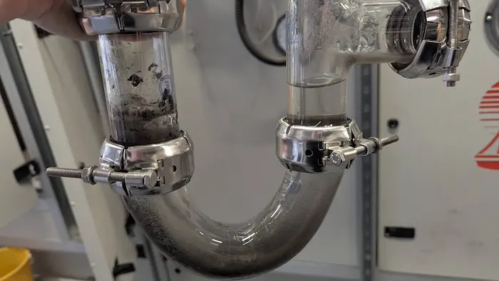 HTM compliant glass trap in a hospital - blackened water indicates dirt in the AHU
